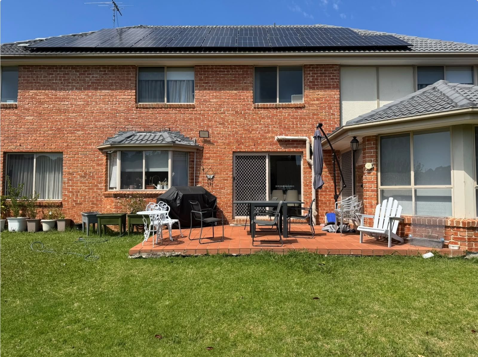 Existing rear of the home with an open tiled patio and lawn